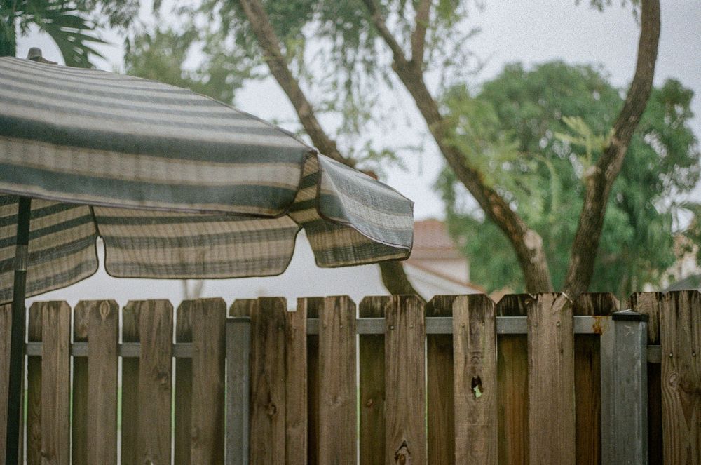 A wooden fence with an awning or canopy visible in an outdoor setting.