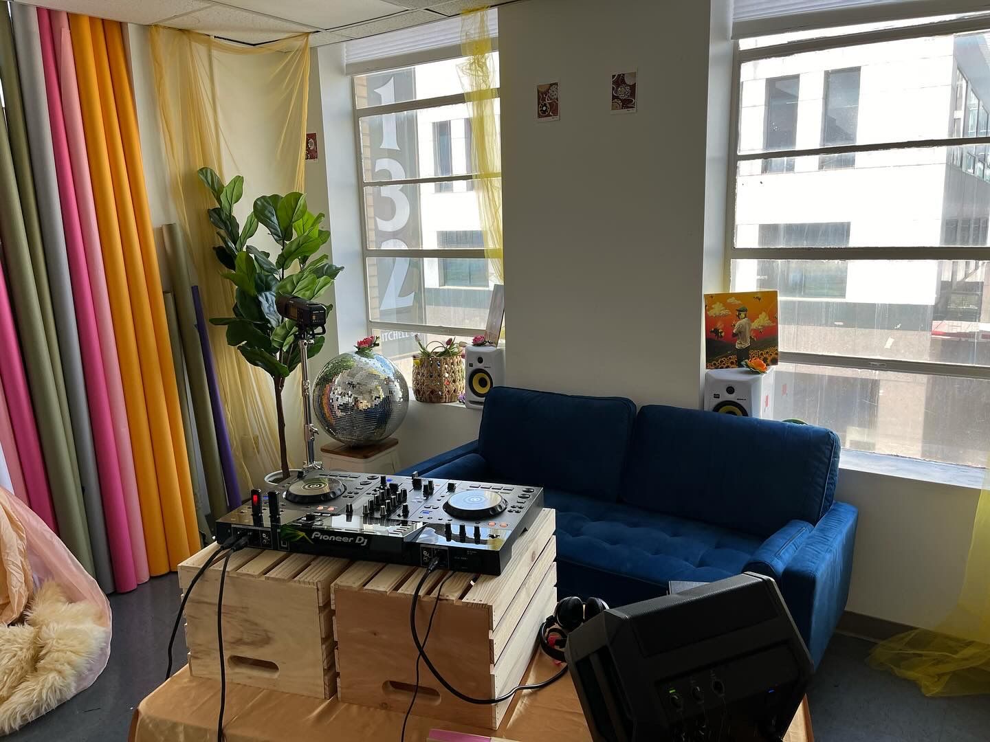 Modern office space with blue couch, striped curtains and DJ equipment setup.