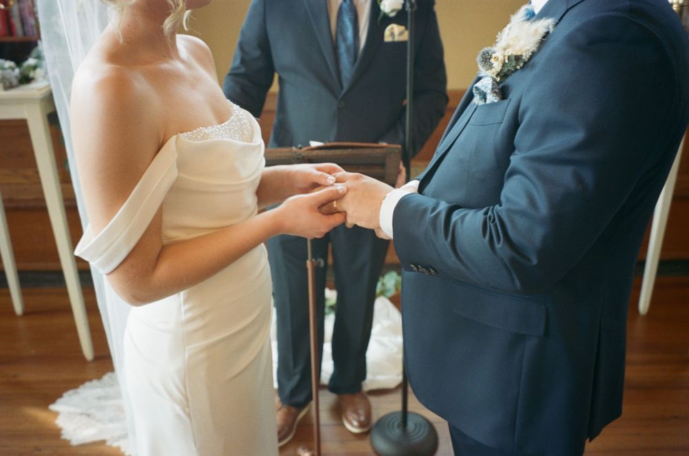 Close-up of wedding ceremony ring exchange under floral arch.