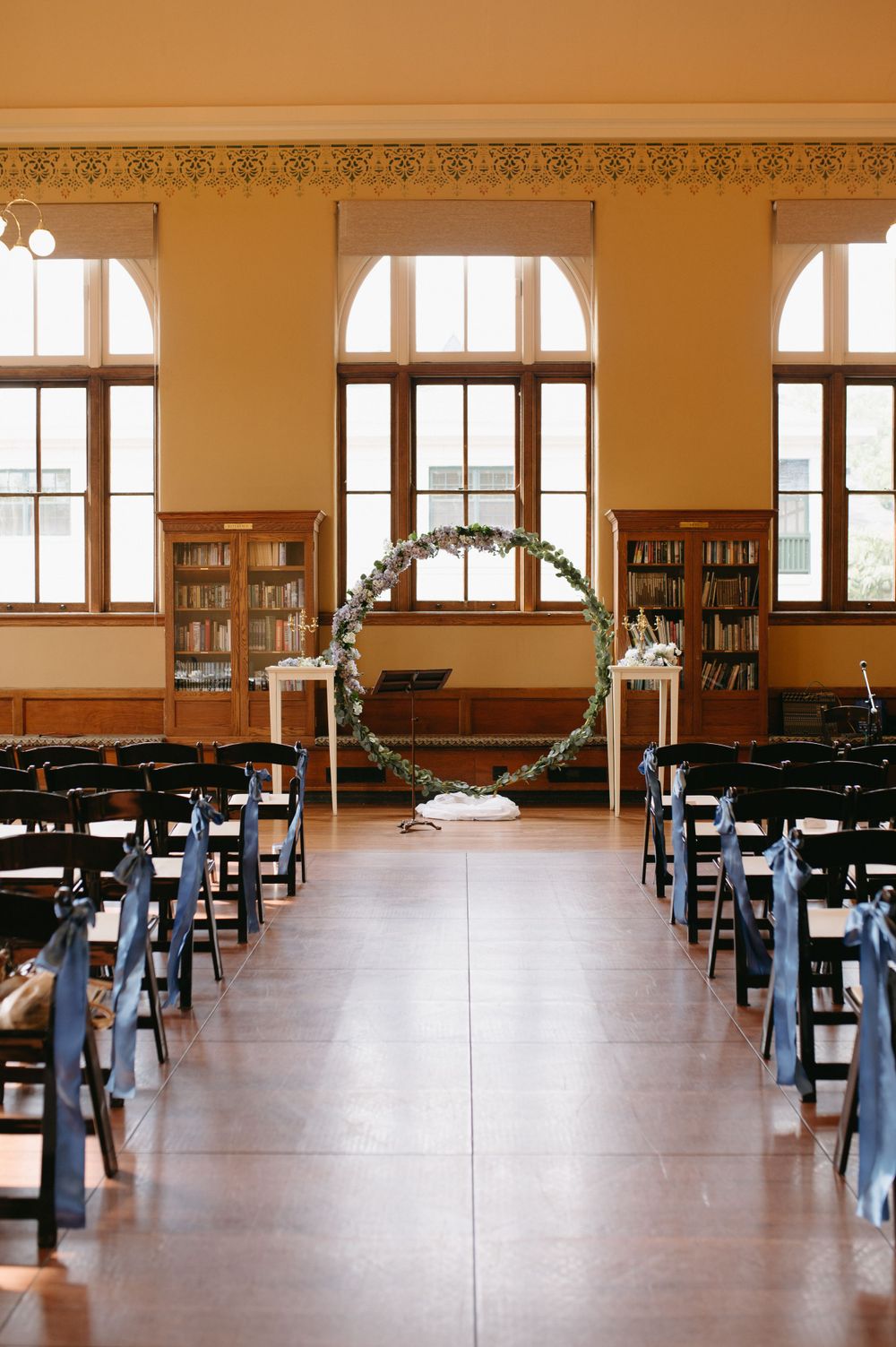 Wedding ceremony setup in library room with circular arch and navy chairs.