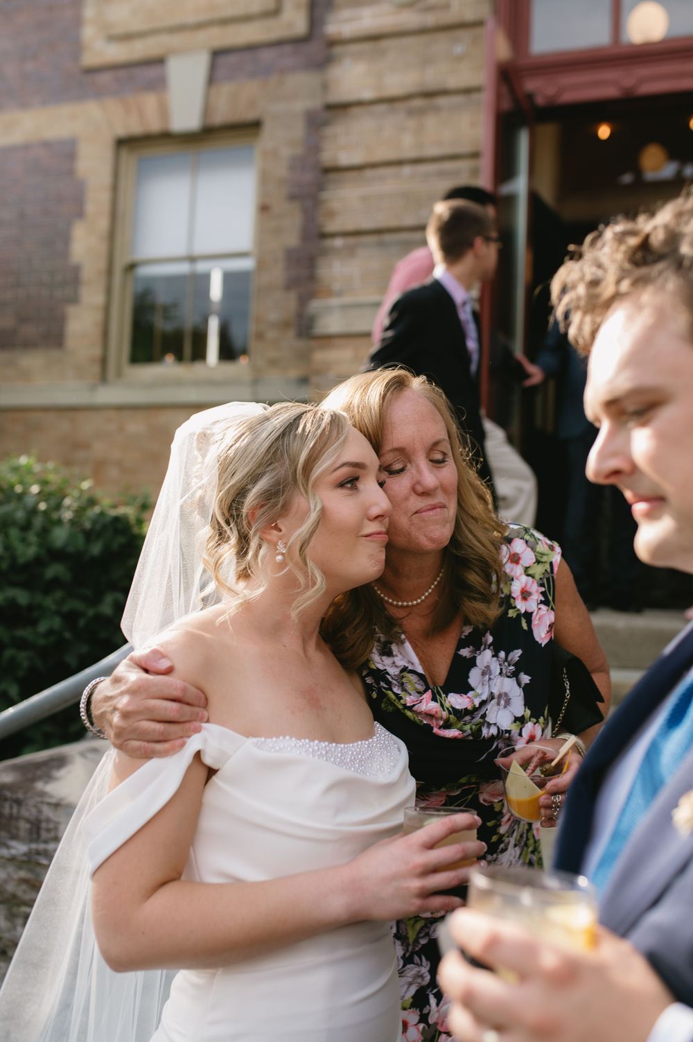 Wedding celebration outside brick building with guests enjoying drinks and conversation.