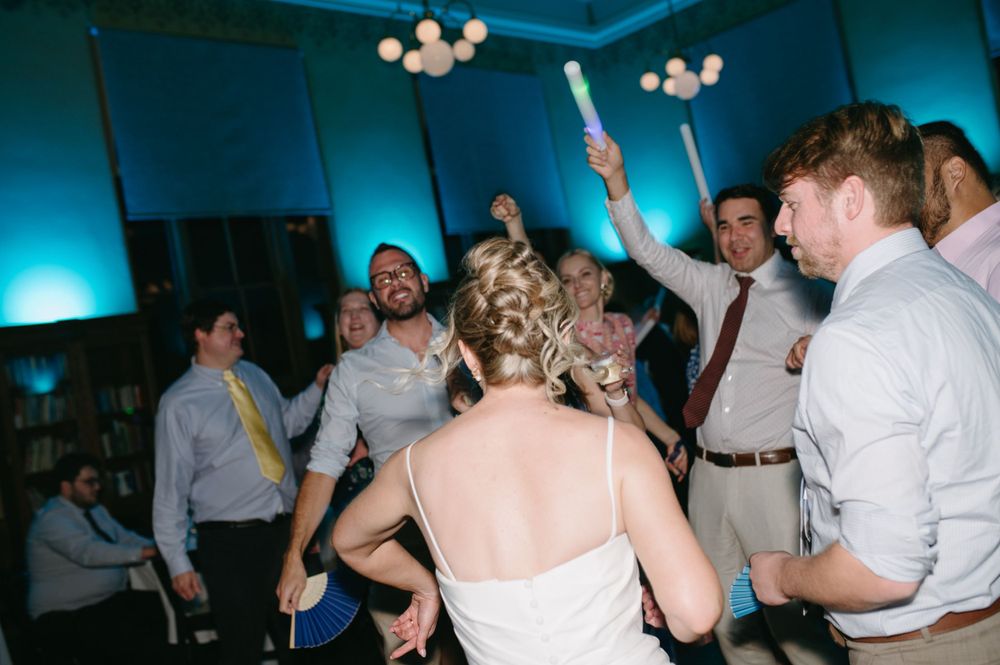 Wedding reception dance floor with guests dancing under blue ambient lighting.