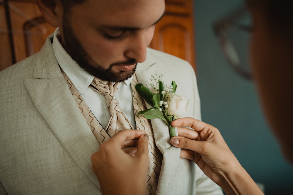 Sister placing a flower on her brother’s (the groom’s) lapel, a loving touch