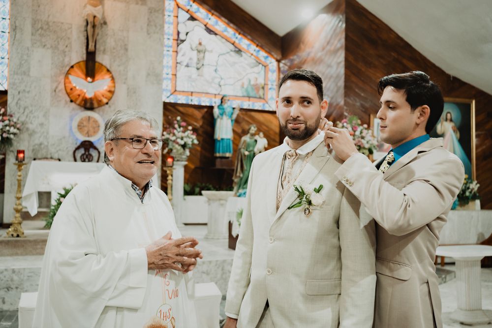 Brother handing a detail to the groom as he waits for the bride at the altar