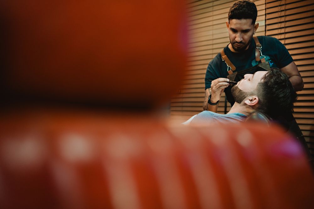 Barber styling the groom’s beard, a detailed shot from the wedding preparation