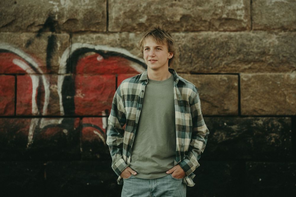 Casual portrait against rustic stone wall with graffiti artwork.