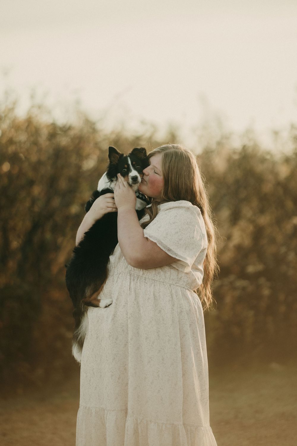 A tender embrace between a person in white and their black and white pet.