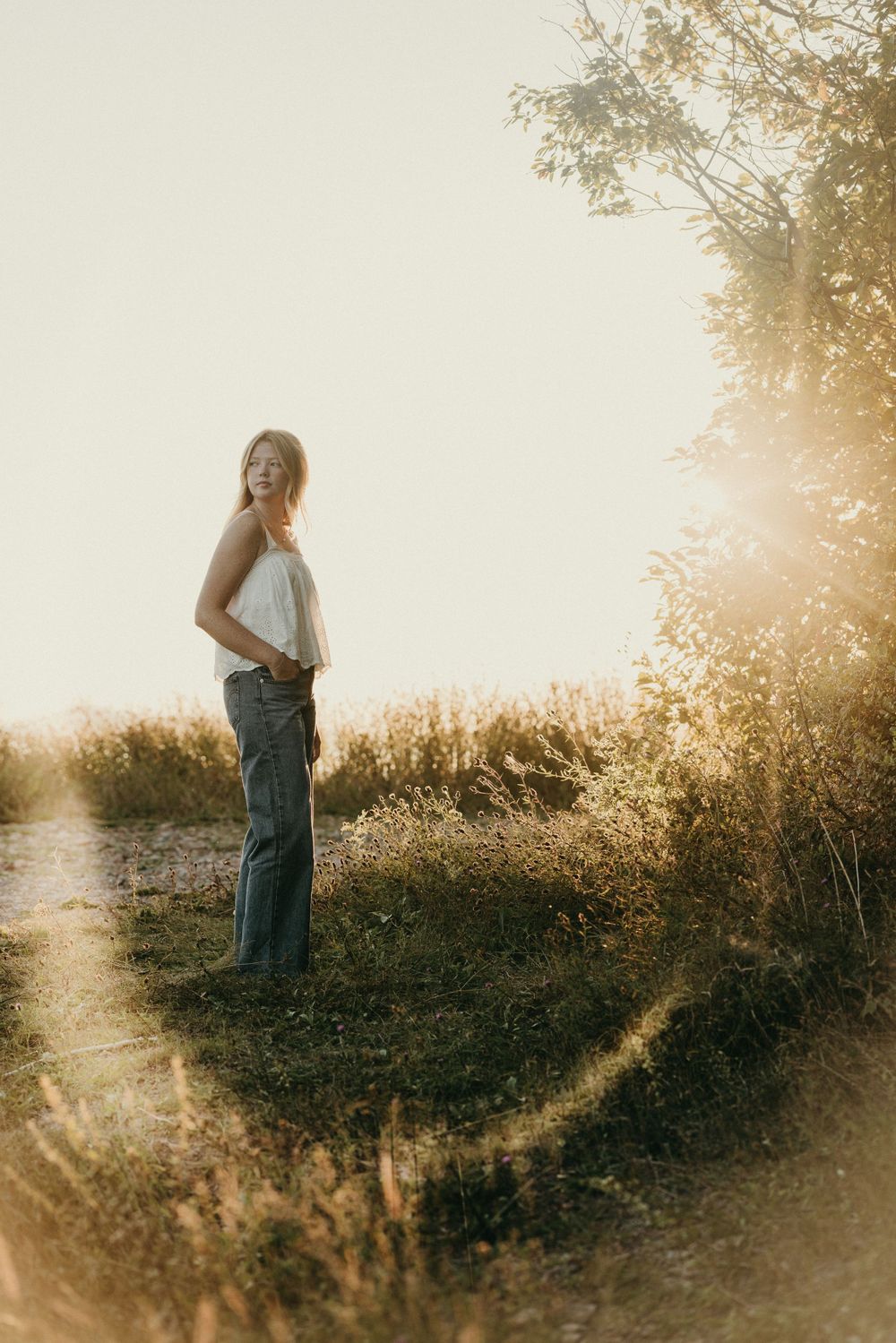 A dreamy golden hour photoshoot in a field with tall grass and wildflowers at sunset.
