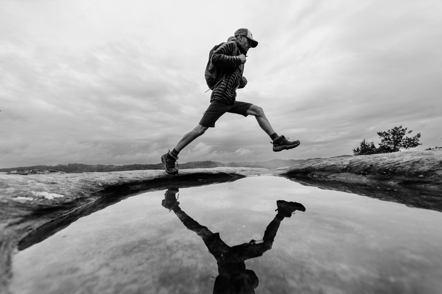 Red River Gorge Hiking | A dynamic black and white shot of someone leaping over a puddle with their reflection visible.