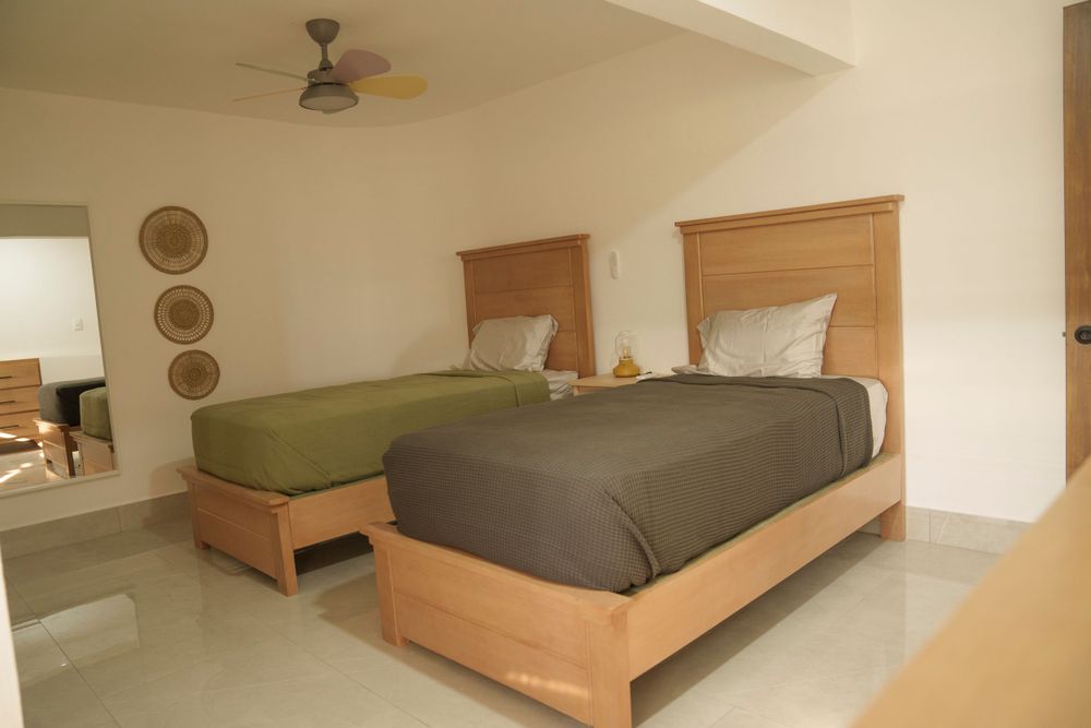 Twin bedroom with wooden bed frames, gray bedding, and ceiling fan.