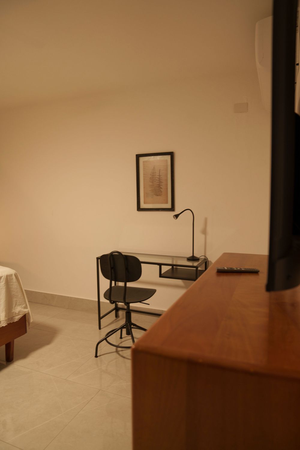 Minimalist study area with black chair, wooden desk, and framed artwork.