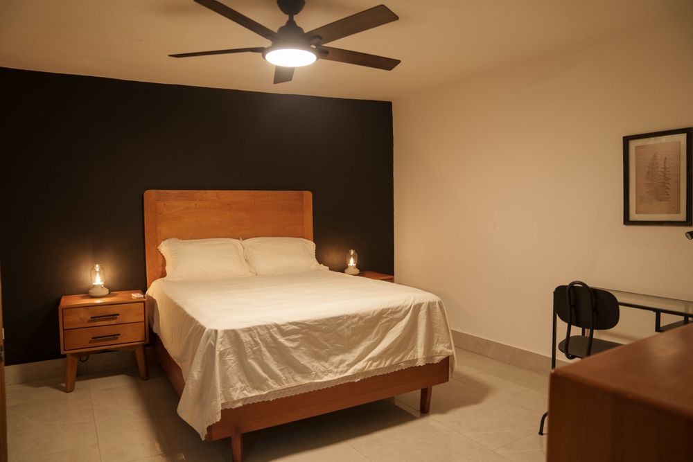 Modern bedroom with wooden furniture, accent wall, and ceiling fan.