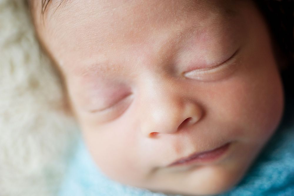 Peaceful newborn boy in a blue swaddle during a Toronto newborn session by Phoebe Lee Photo