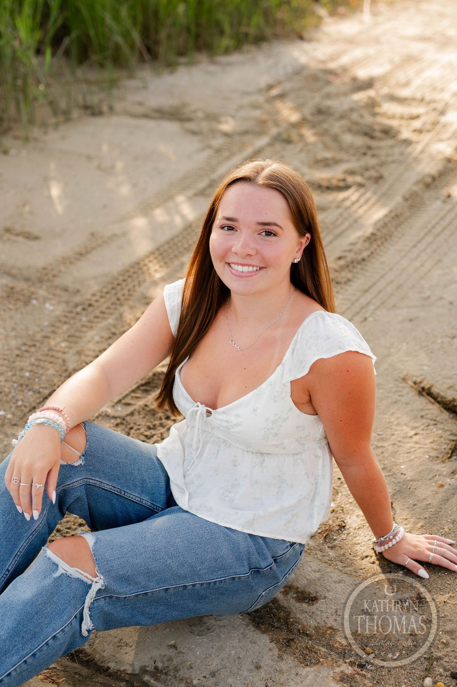 A sunny portrait session on a sandy trail with natural greenery in the background.