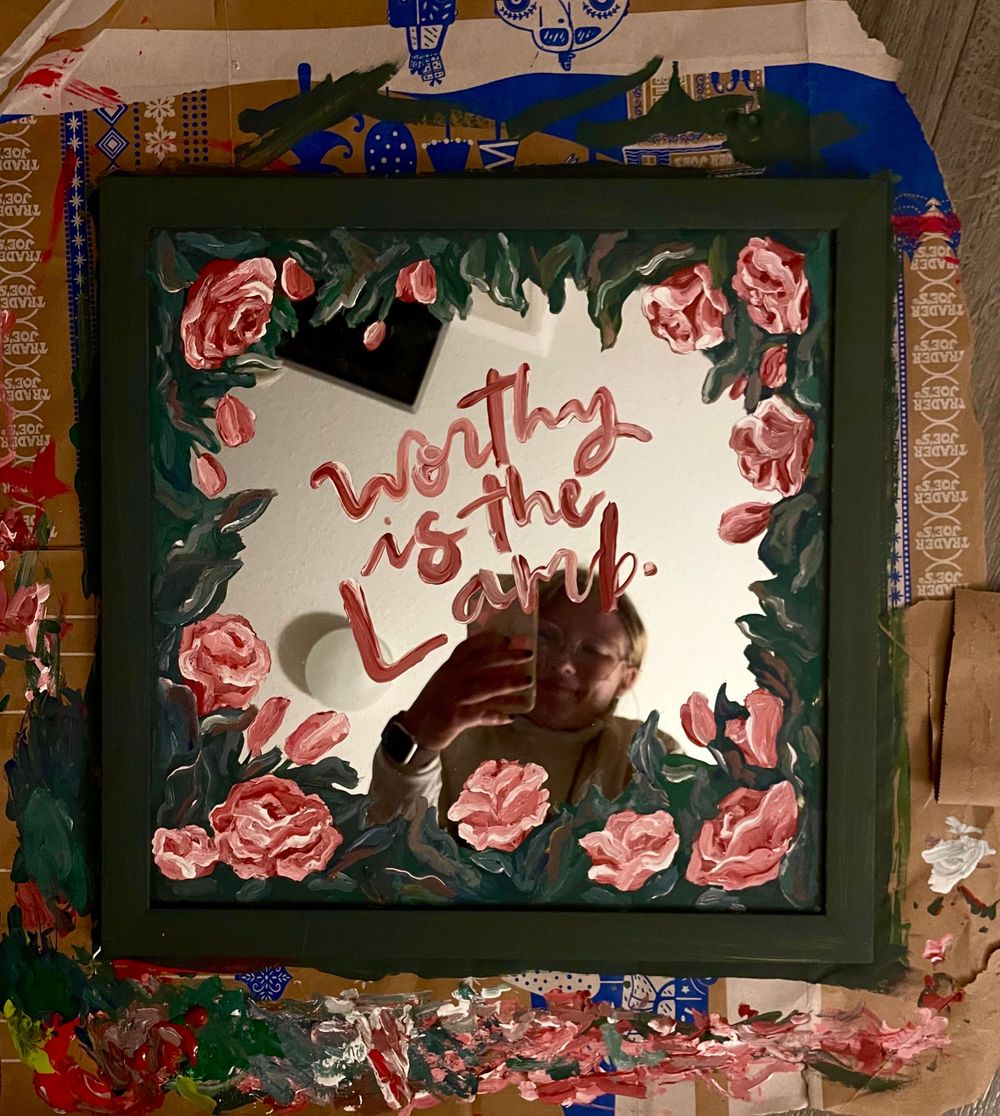 Decorative wall display with pink roses and text in red framed by dark borders.