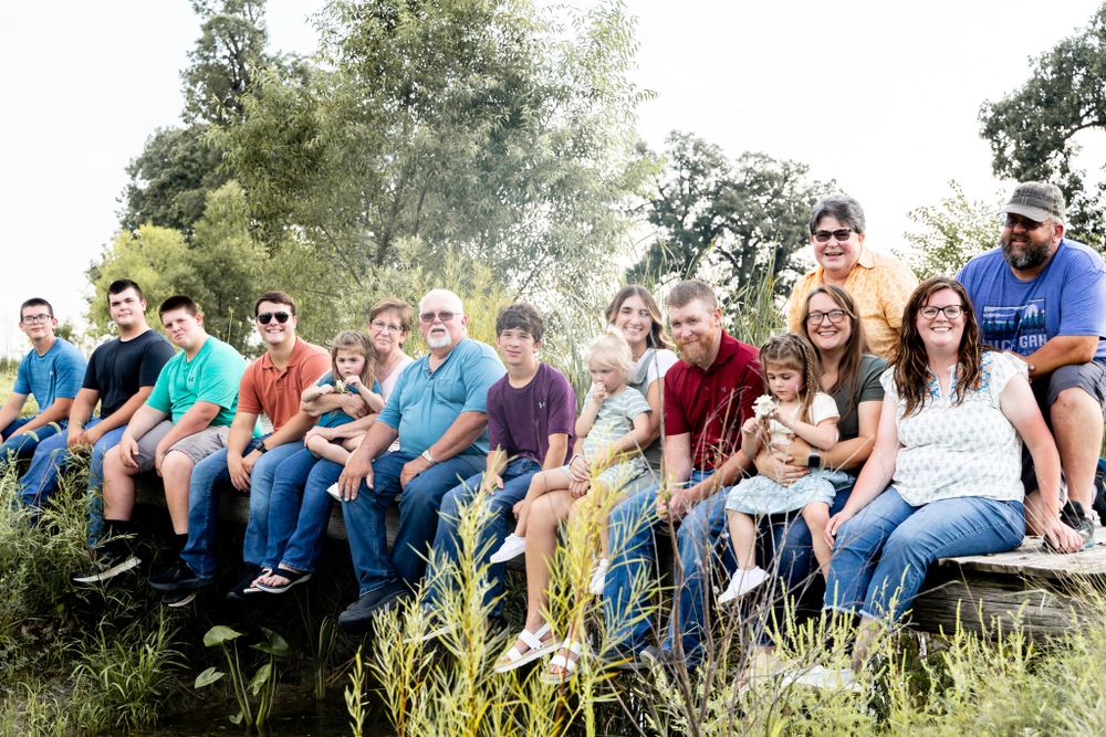 A large family group seated on wooden bleachers outdoors for a photo.
