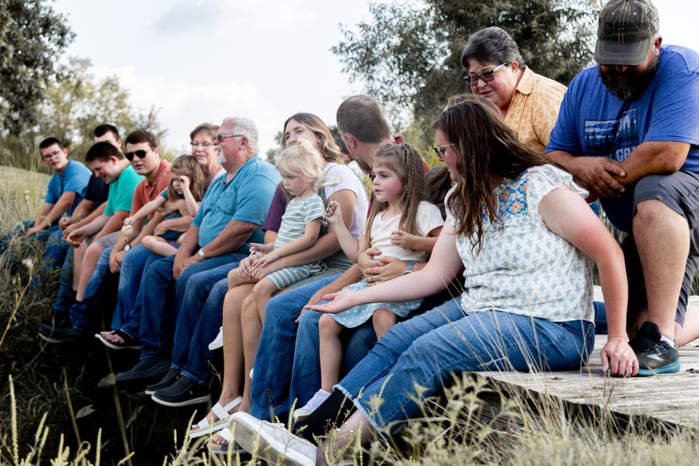 People sitting in a row on wooden bleachers during an outdoor gathering.