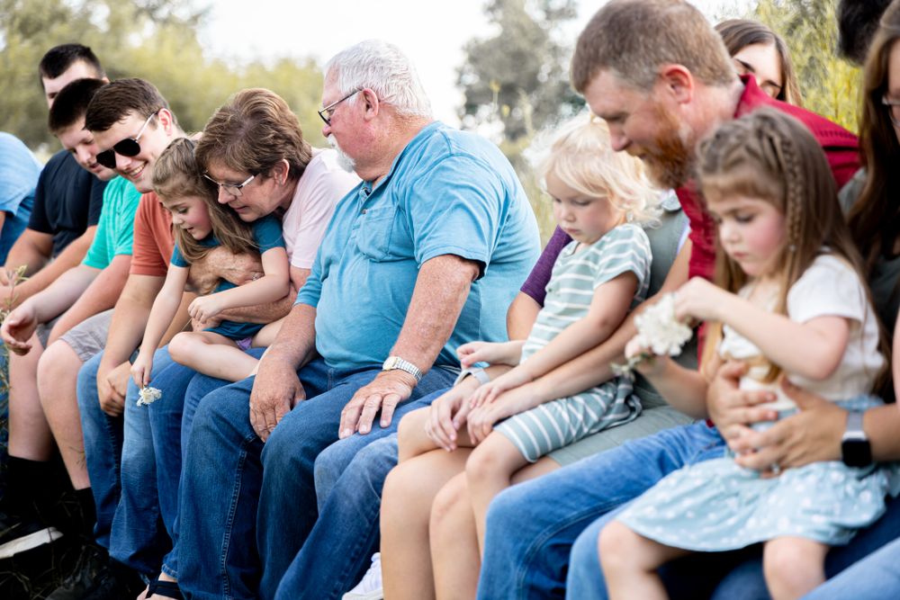 A casual family gathering shows multiple generations seated together on outdoor bleachers.