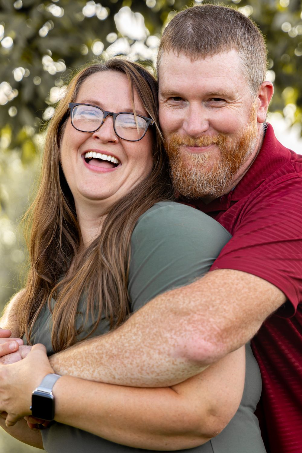 A joyful couple sharing a loving embrace outdoors with bokeh lighting in the background.