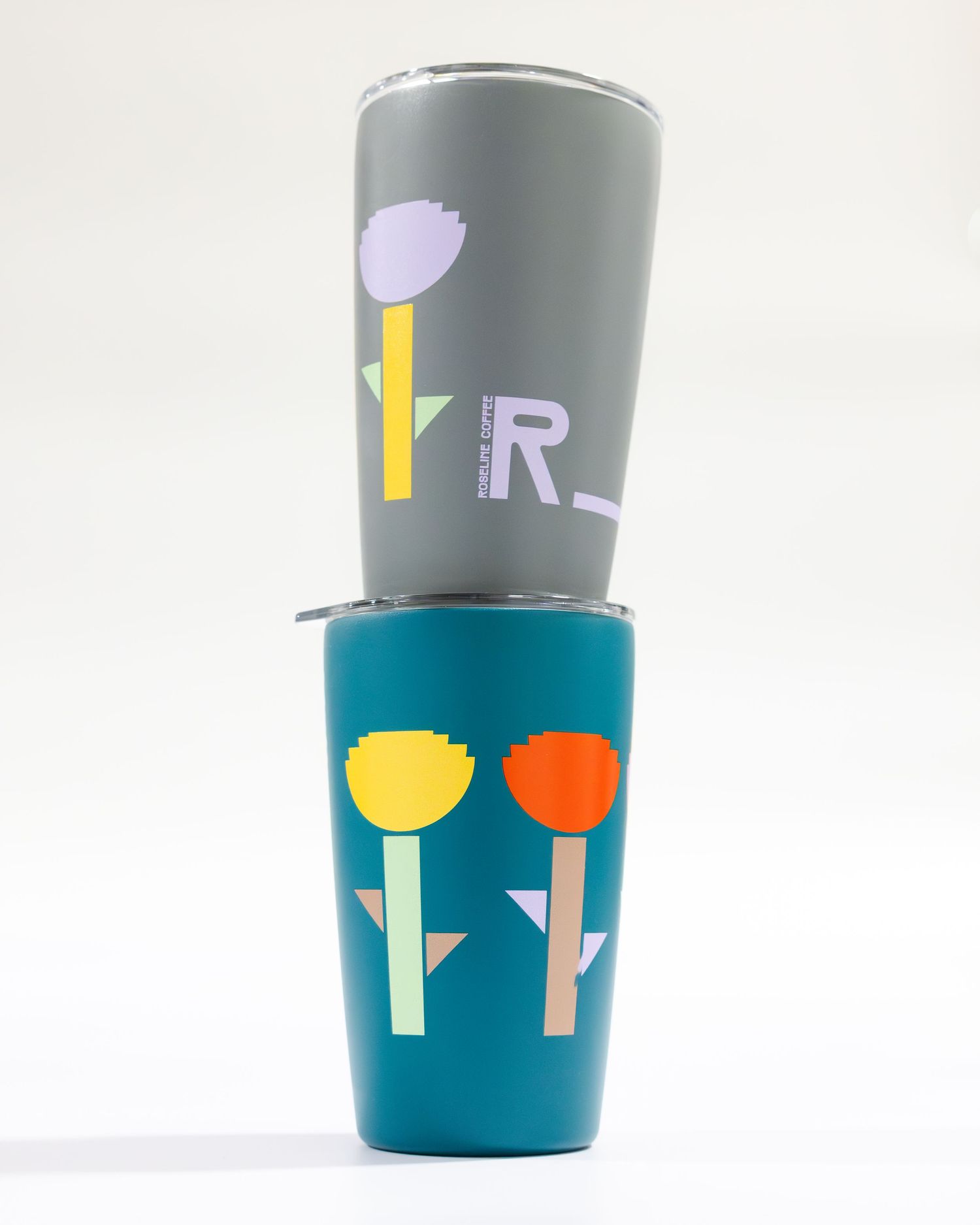 Two stacked tumblers featuring minimalist floral designs in gray and turquoise colors with yellow, orange and purple accents.