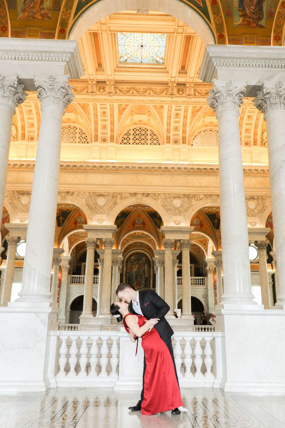A couple dances in an elegant pose inside the ornate Library of Congress Great Hall with its grand columns and architecture.