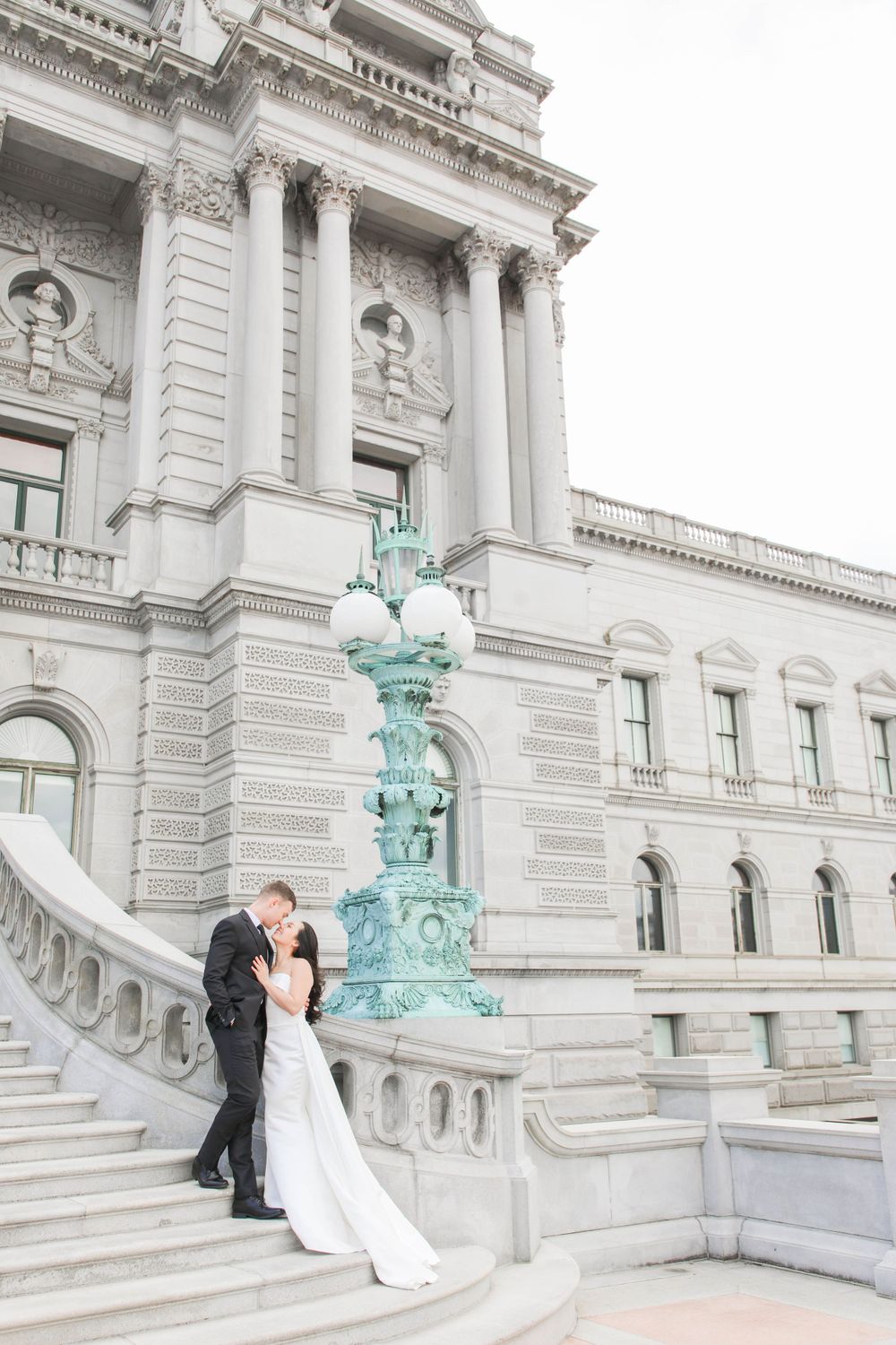 A romantic scene on the grand steps of the Library of Congress with ornate architecture and turquoise lamp posts.