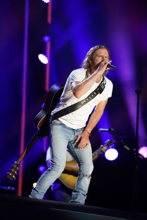 Country music performance on stage with moody blue lighting and acoustic guitar.