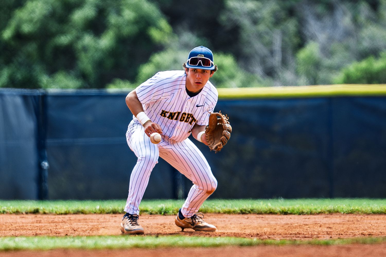 Baseball player in pinstriped uniform ready in fielding position at infield.