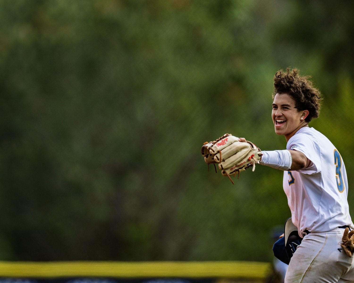 Baseball infielder celebrates while making a play with glove raised.