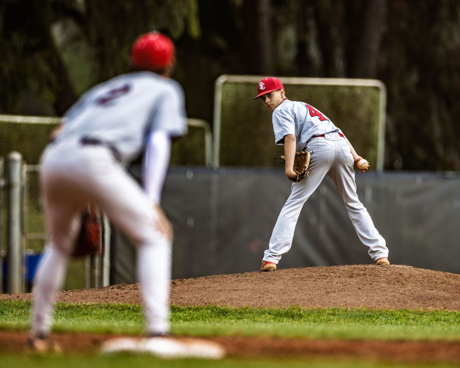 Baseball pitcher in mid-delivery motion on the mound during a game.