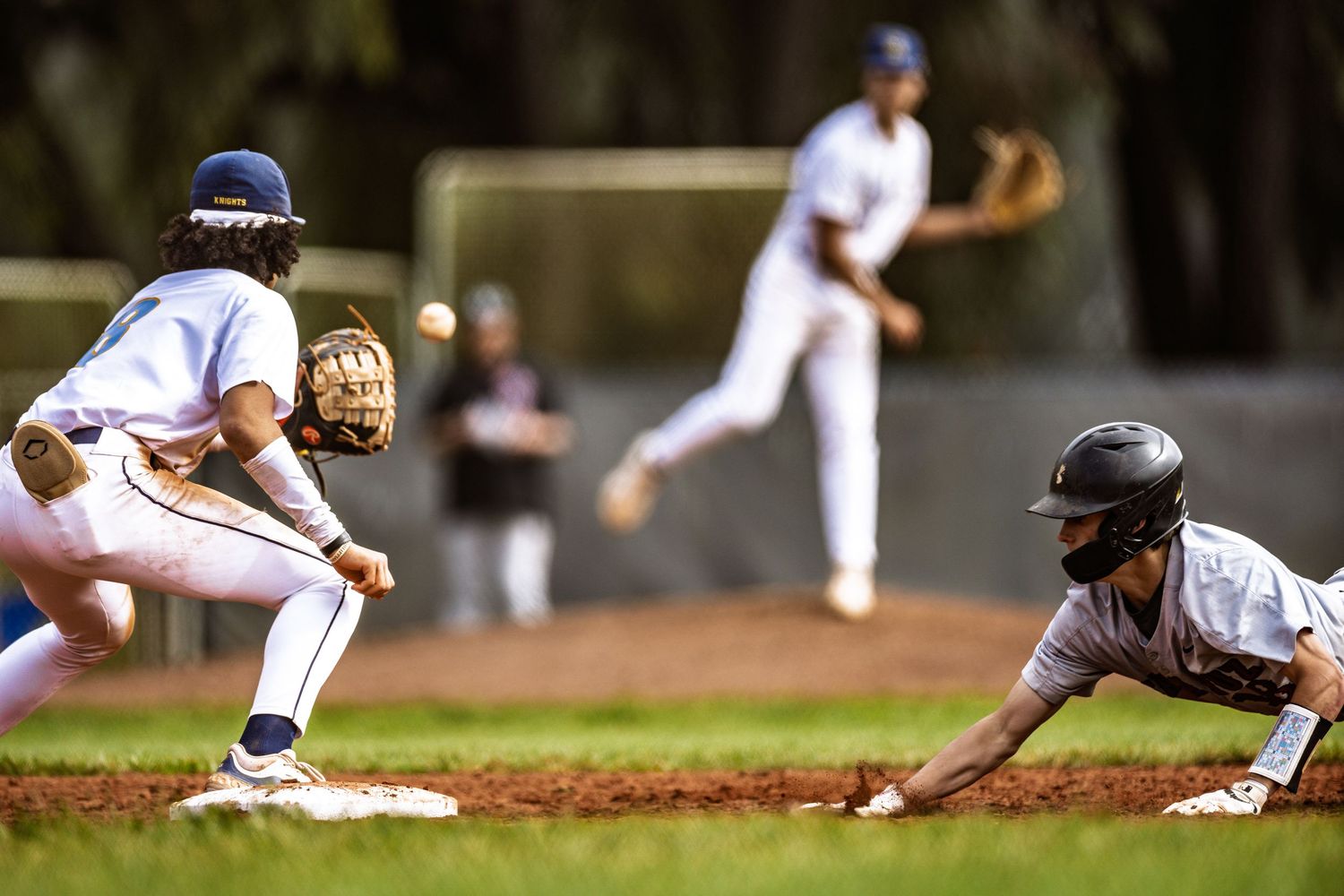 Baserunner slides into base as catcher prepares to make the tag during baseball game.