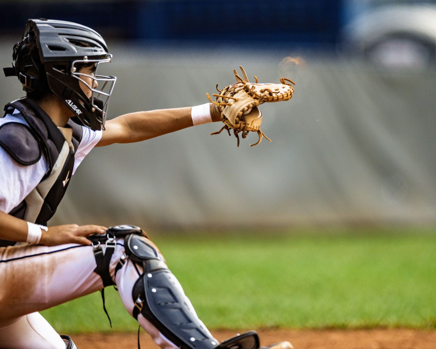 Baseball catcher in gear shows glove to camera during game.