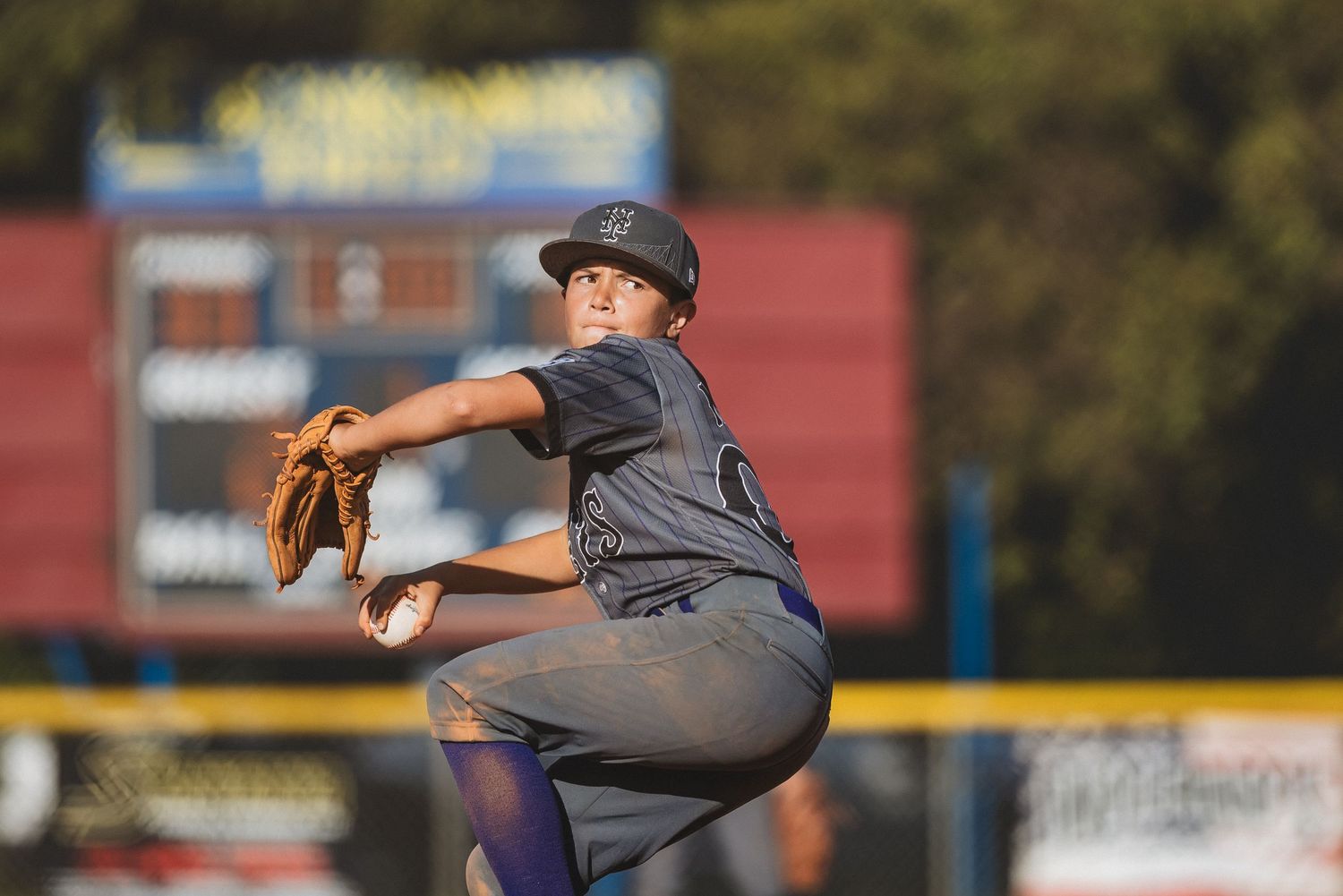 A baseball pitcher in a gray uniform mid-windup on the mound during a game.