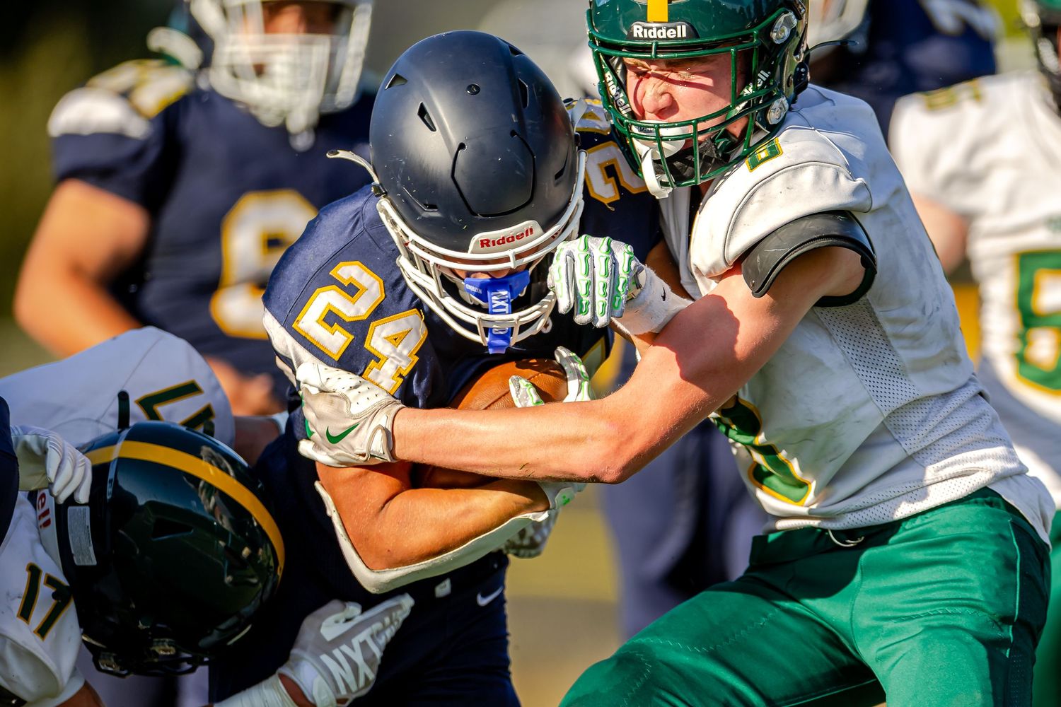 Football players in green and white uniforms competing on the field during an intense game situation.