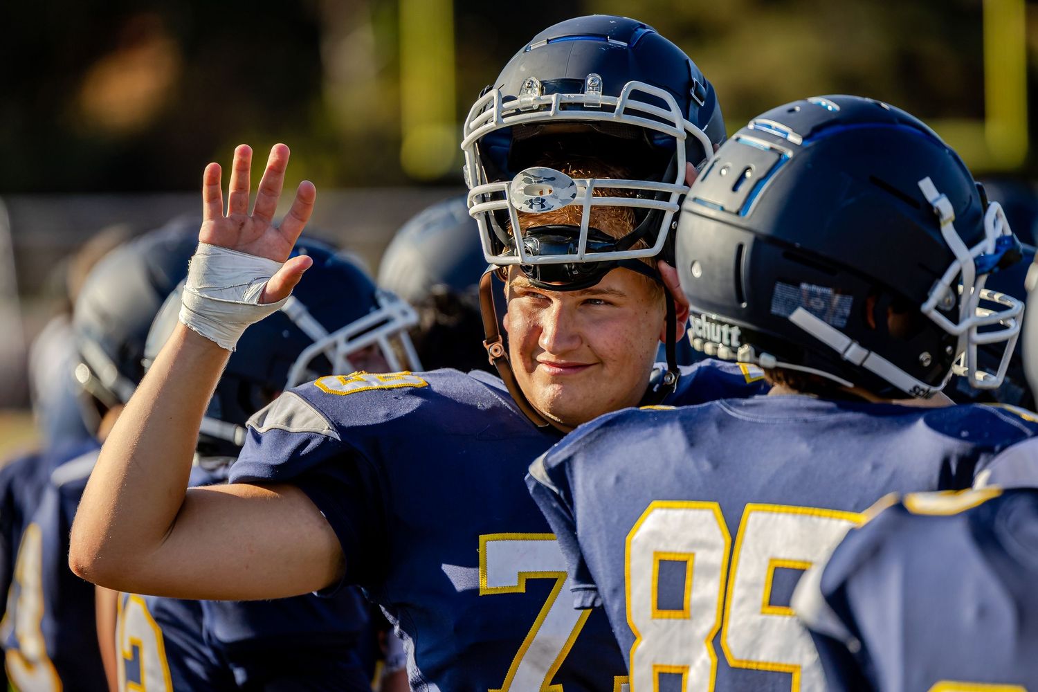 Two football players in navy blue uniforms celebrating together on field during a game.