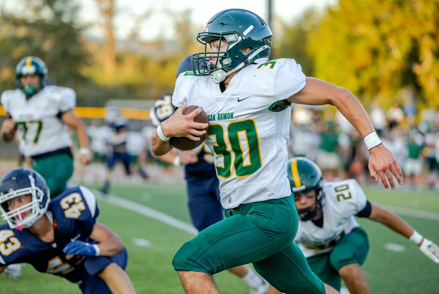 Football players in green and white jerseys clash with opponents in blue uniforms during an intense game.