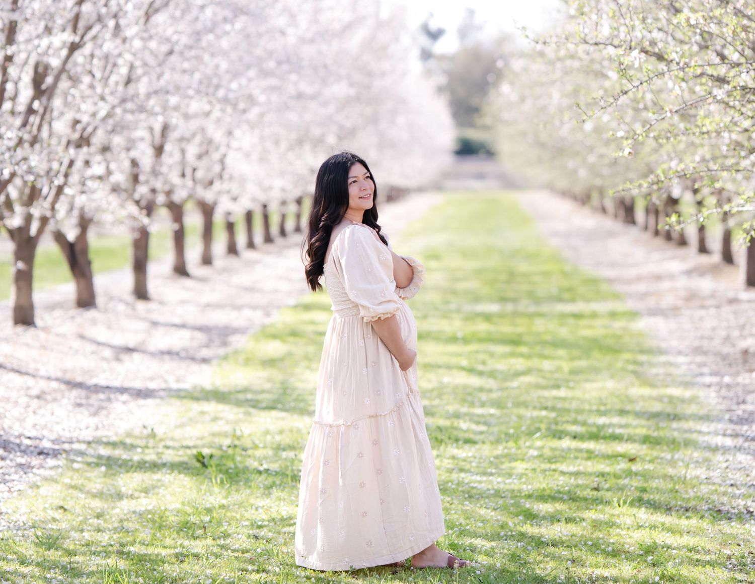 Pregnant woman gazing at her partner, with cherry blossoms surrounding them, evoking a sense of peace and anticipation for their new arrival