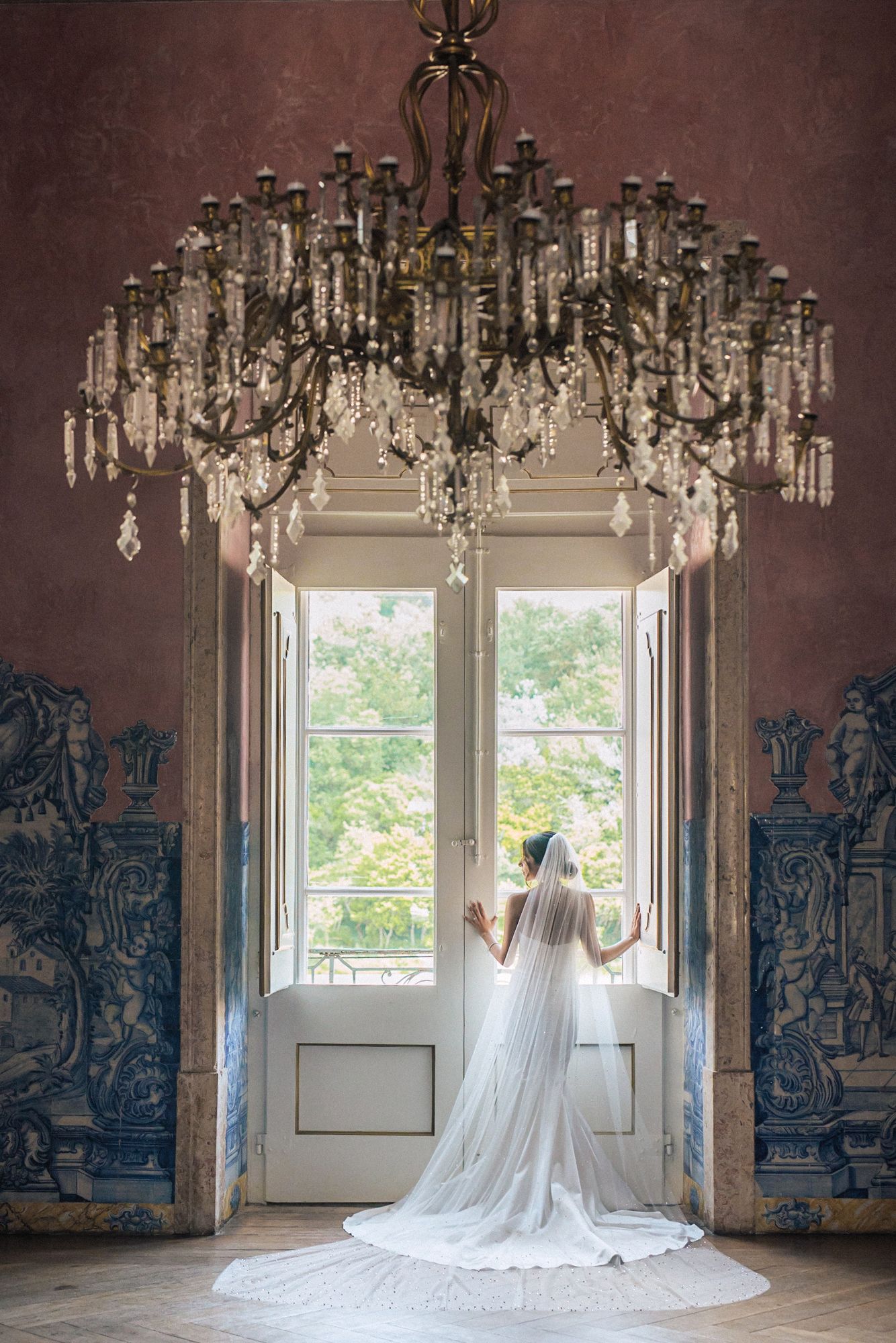 Bride at a large window photographed by an Indian destination wedding photographer in Portugal – Correio Mor Palace