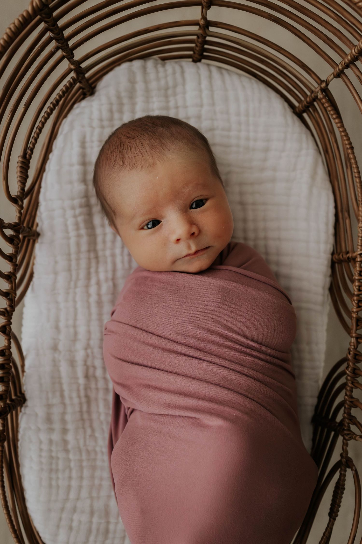 Close-up photo of a baby's delicate hand resting on their soft bare skin in warm lighting.
