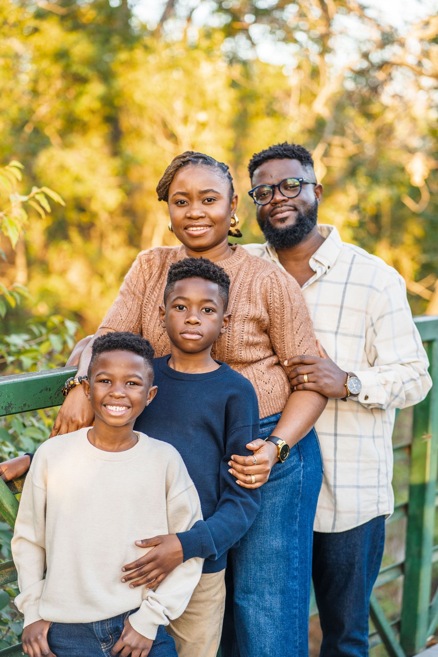 Family wearing coordinated neutral outfits poses together outdoors during golden hour.