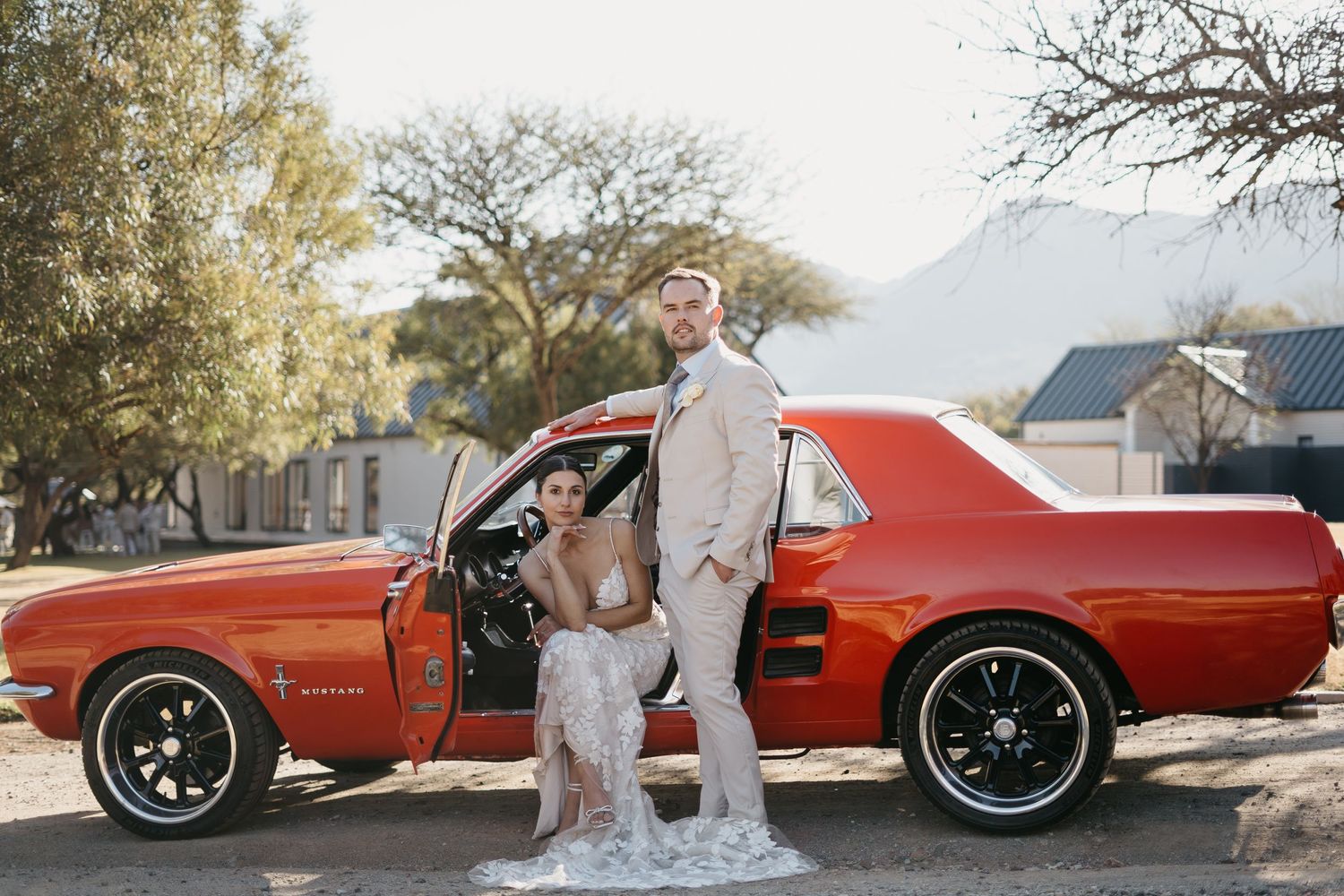 bride and groom looking all timeless and romantic posing with red mustang vintage car on their wedding day at Artelier in South Africa