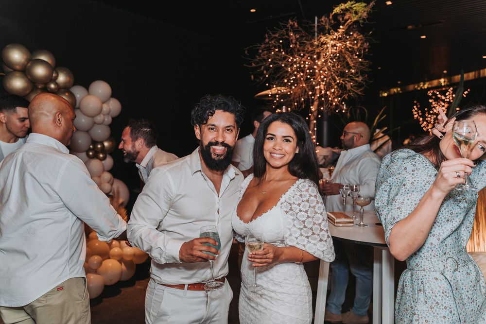 Wedding reception party guests celebrating on dance floor with sparklers and champagne in dimly lit venue.