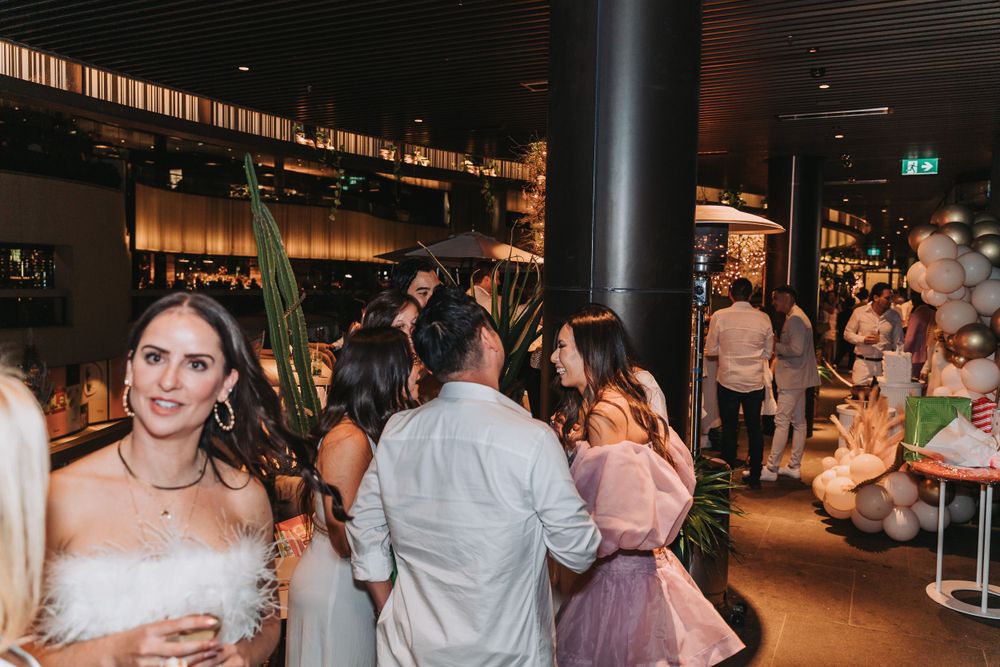People gather in a dimly lit upscale bar or restaurant venue with modern decor and warm ambient lighting.