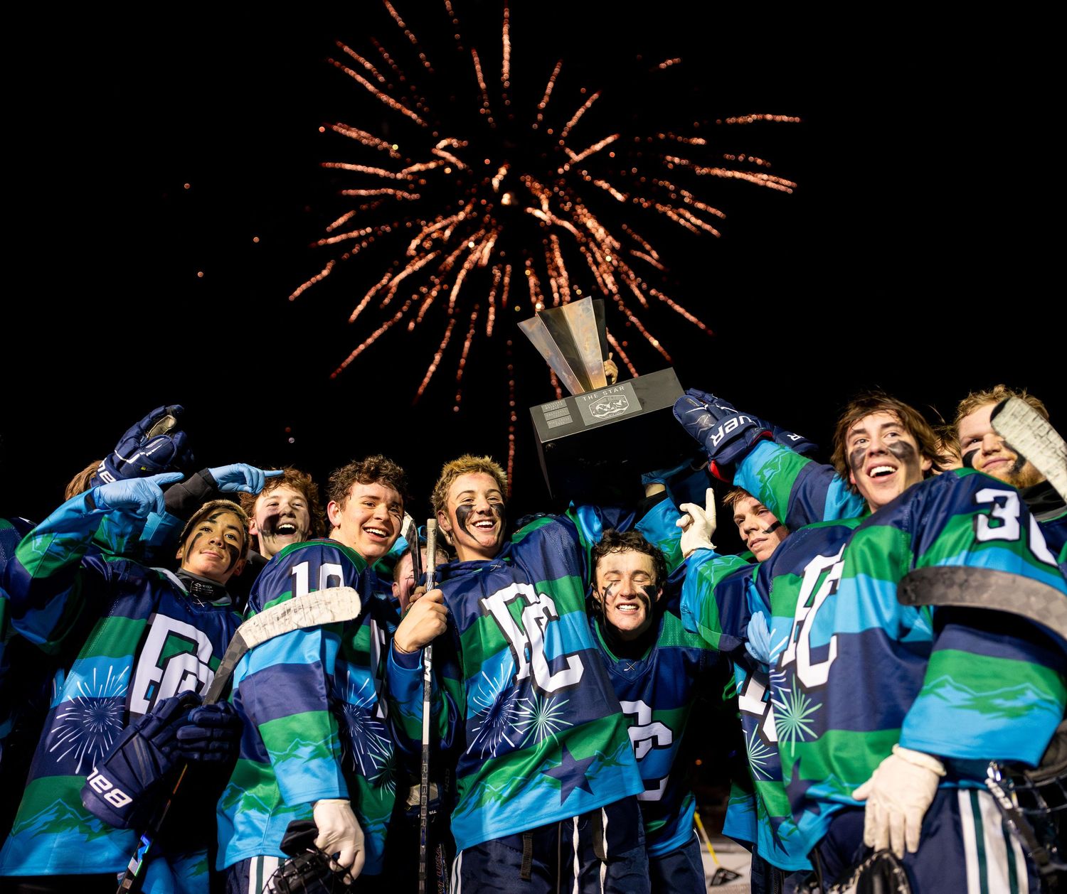 Hockey team celebrates victory with fireworks display in night sky.