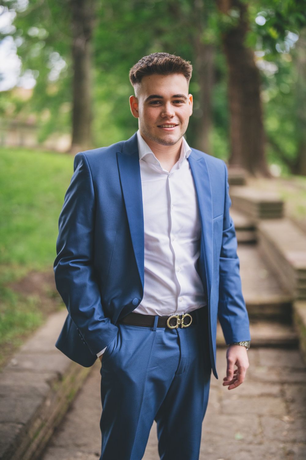 Person in a blue suit standing on stone steps in a park setting.