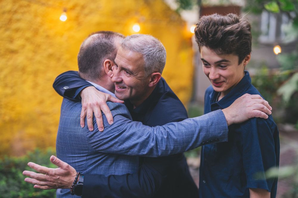 Warm embrace shared between people in blue jackets during an outdoor gathering.