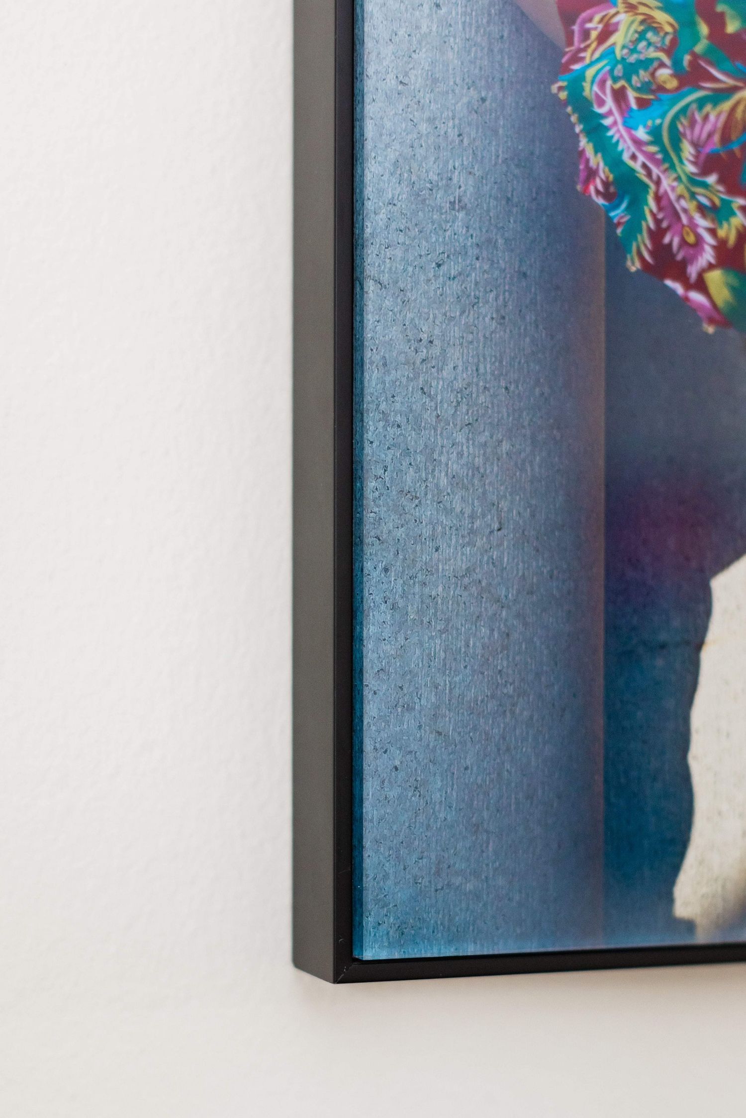Close-up view of a blue picture frame corner mounted on a white wall.