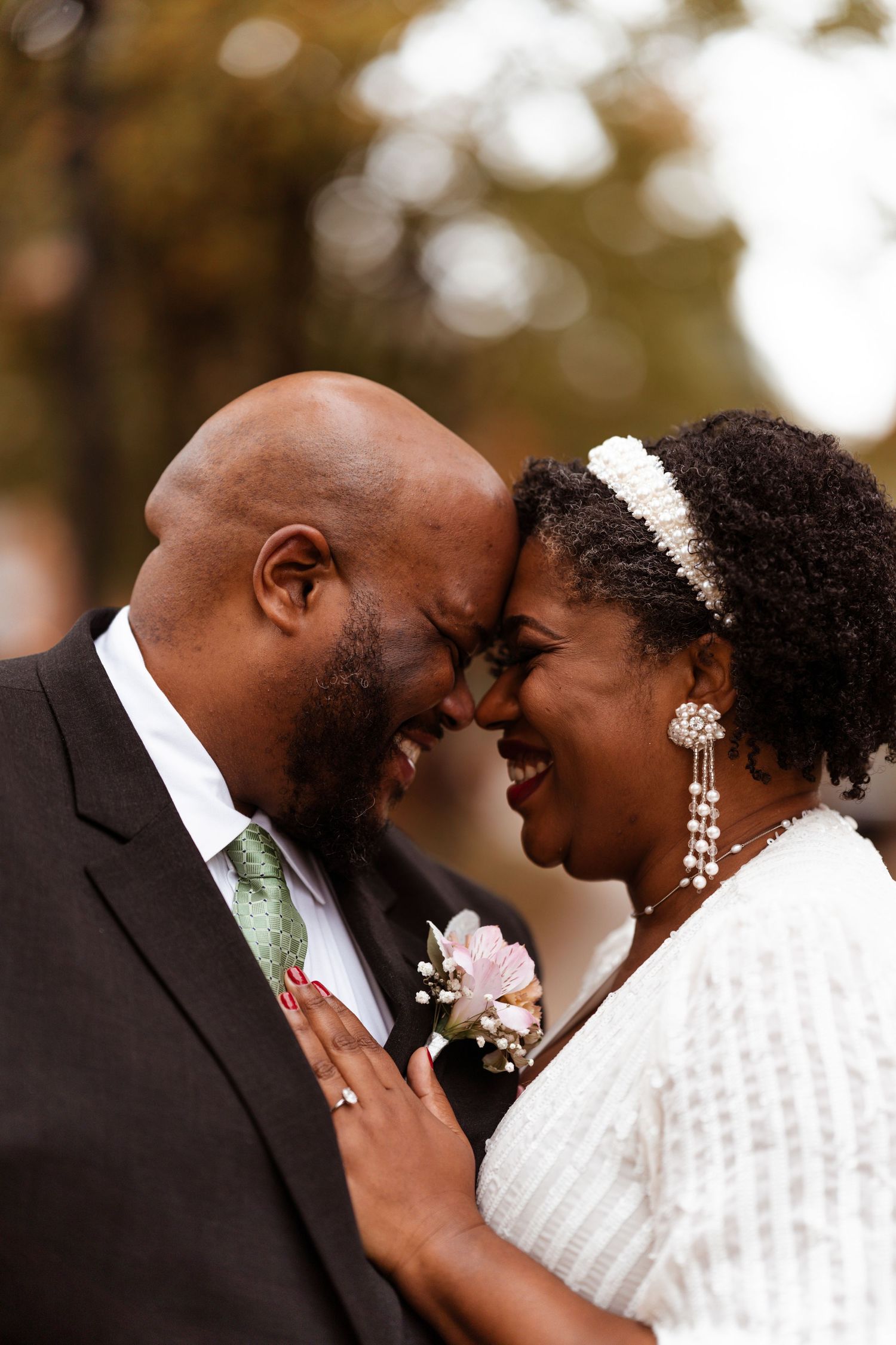 A romantic wedding portrait of a couple sharing an intimate moment, with the bride wearing white and sparkly jewelry.