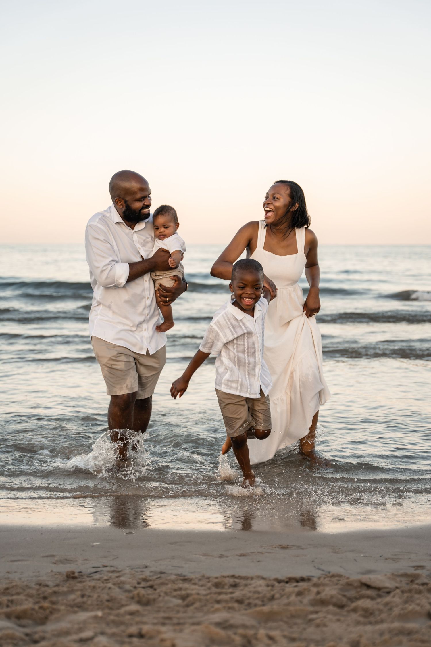Family of 4 running out of the water on a beach in Alicante Spain wearing all white outfits family photos