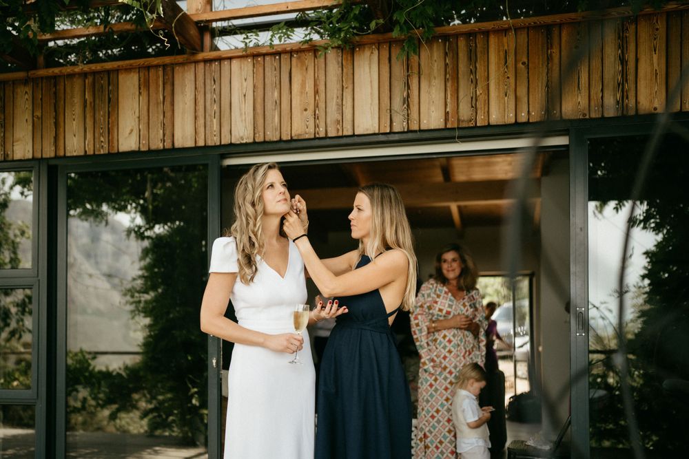Wedding day preparations on a wooden deck with guests gathering in the background.